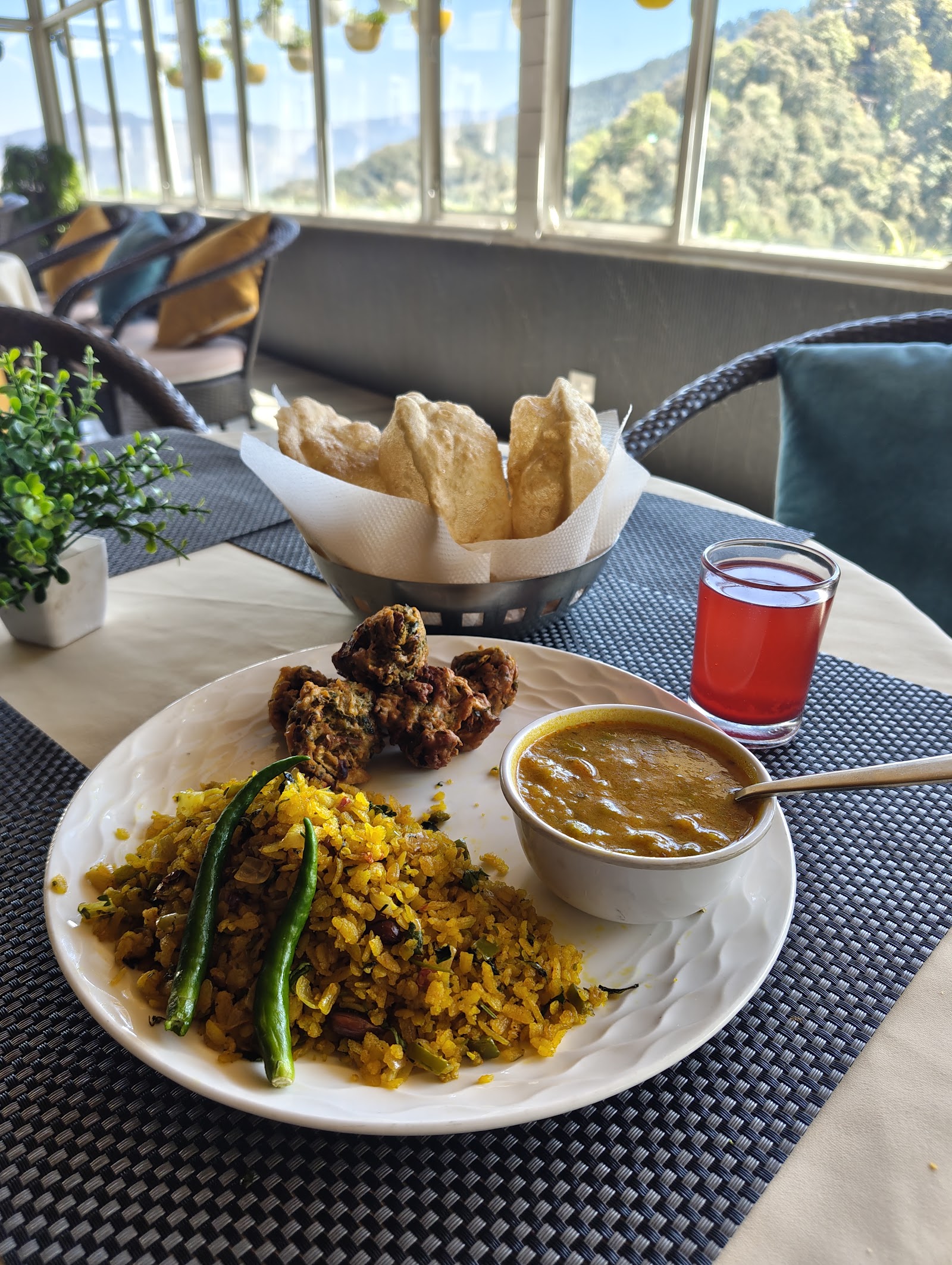 Breakfast plate with puris and dal served with a valley view at Deodar Kitchen